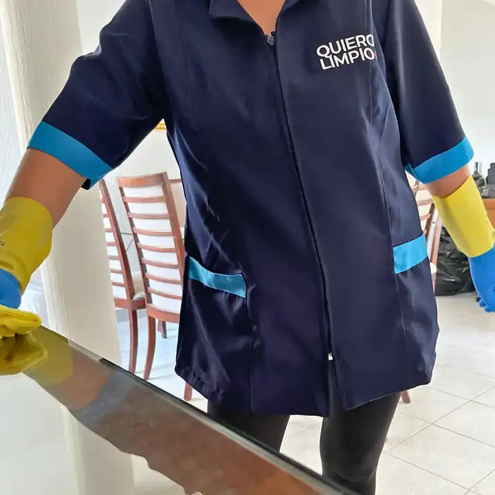 Colaboradora de Quiero Limpio con uniforme y guantes limpiando una superficie de cristal en una casa de Guadalupe Tepeyac